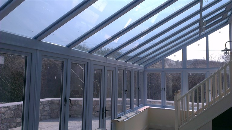 Duck egg blue conservatory with Residence 9 windows and aluminium bifolding doors